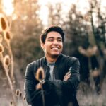 smiling man standing near green trees