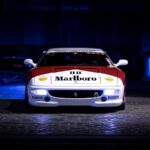 A red and white racing car with visible branding, captured at night in a garage.